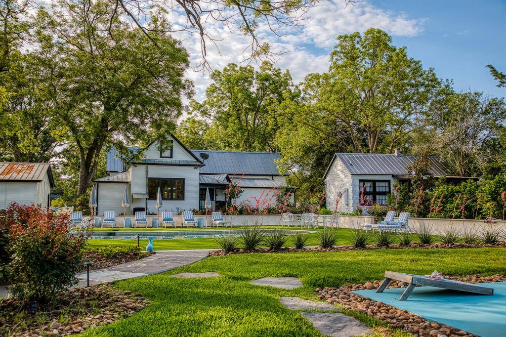A wide angle view captures the lush grounds, sparkling pool, and two character-filled cottages side by side. The Cotton Pearl offers intentional design & relaxed luxury in every detail.