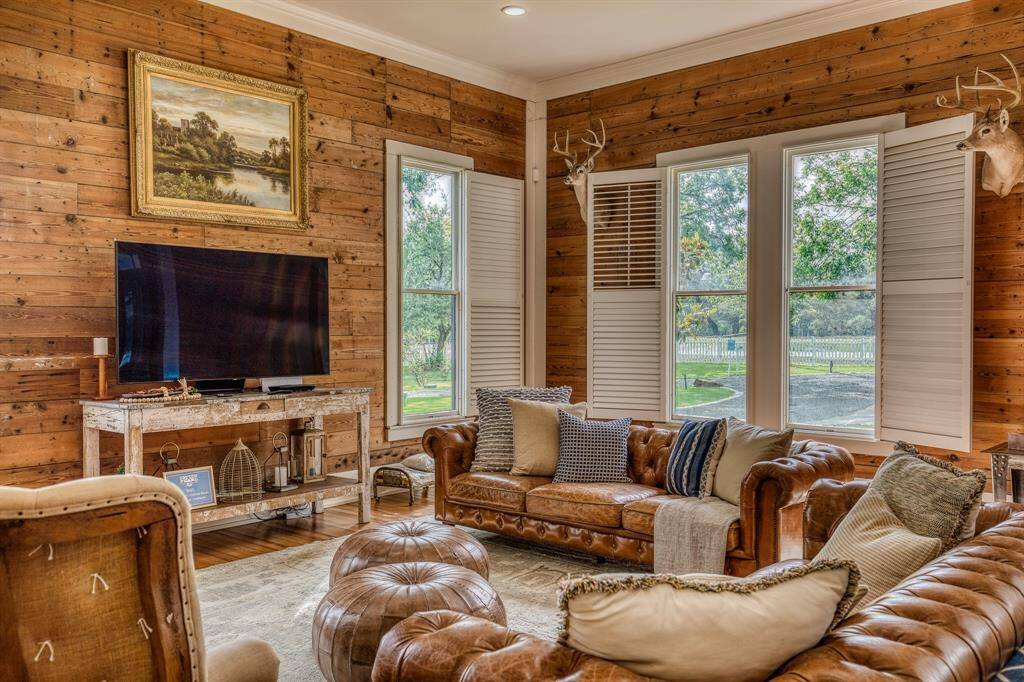 The Cottontail's living room is anchored by rich wood-paneled walls, vintage shutters, & classic leather seating. This inviting space effortlessly blends sophistication with the comfort of country living, making it the perfect backdrop for both quiet evenings & casual entertaining.