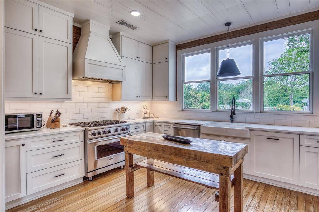 Oversized windows draw the outdoors in, while designer stainless steel appliances elevate this airy, farmhouse-inspired chef’s kitchen.