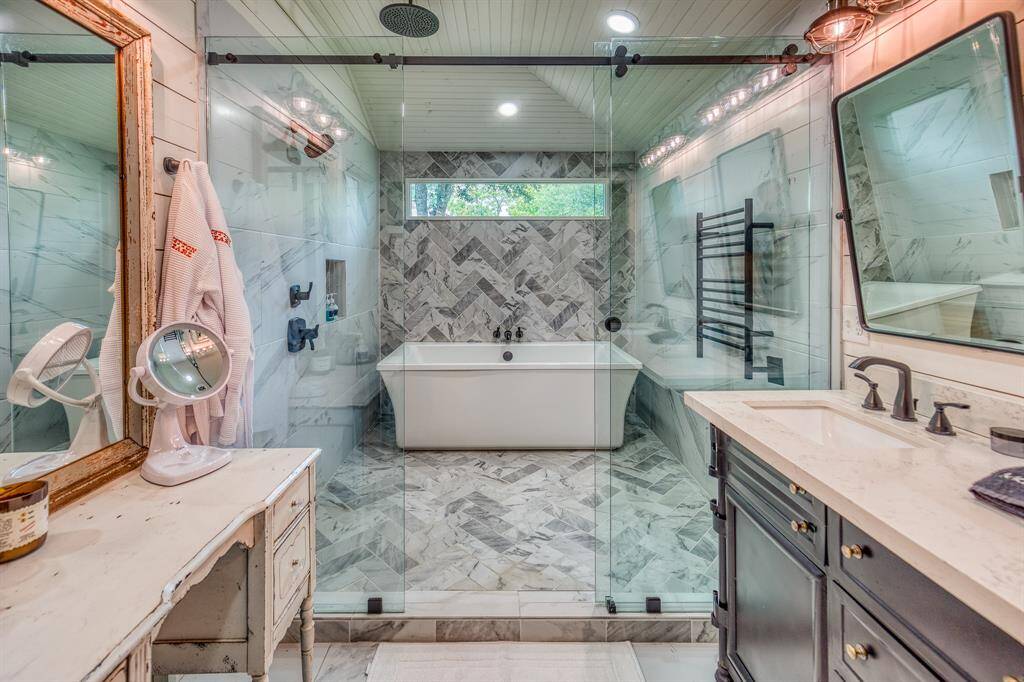 Encased in glass and wrapped in herringbone marble tile, the walk-in wet room combines an oversized soaking tub and rainfall shower for the ultimate indulgence.