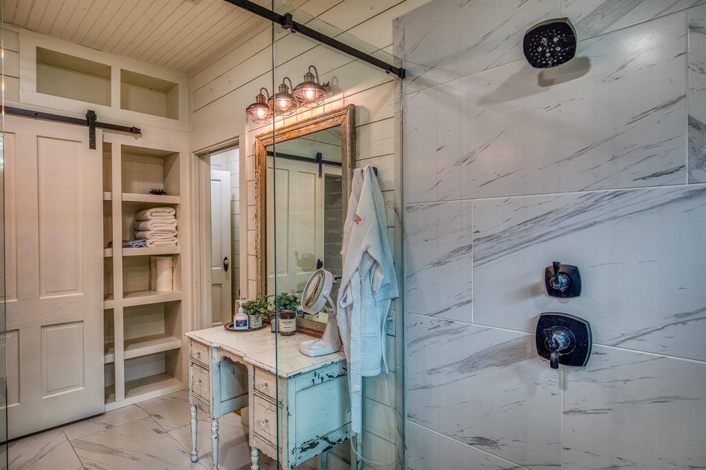 Tucked beside the primary shower, this vintage-style vanity setup is a nod to old-world charm. Custom builtins hidden behind the barn door add functionality to the space.