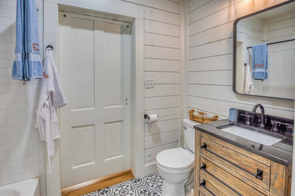 A mix of rustic wood textures, soft shiplap, and classic patterned tile brings personality and polish to this perfectly appointed secondary bathroom. Not pictured, the shower tub combo boasts subway tile backsplash.