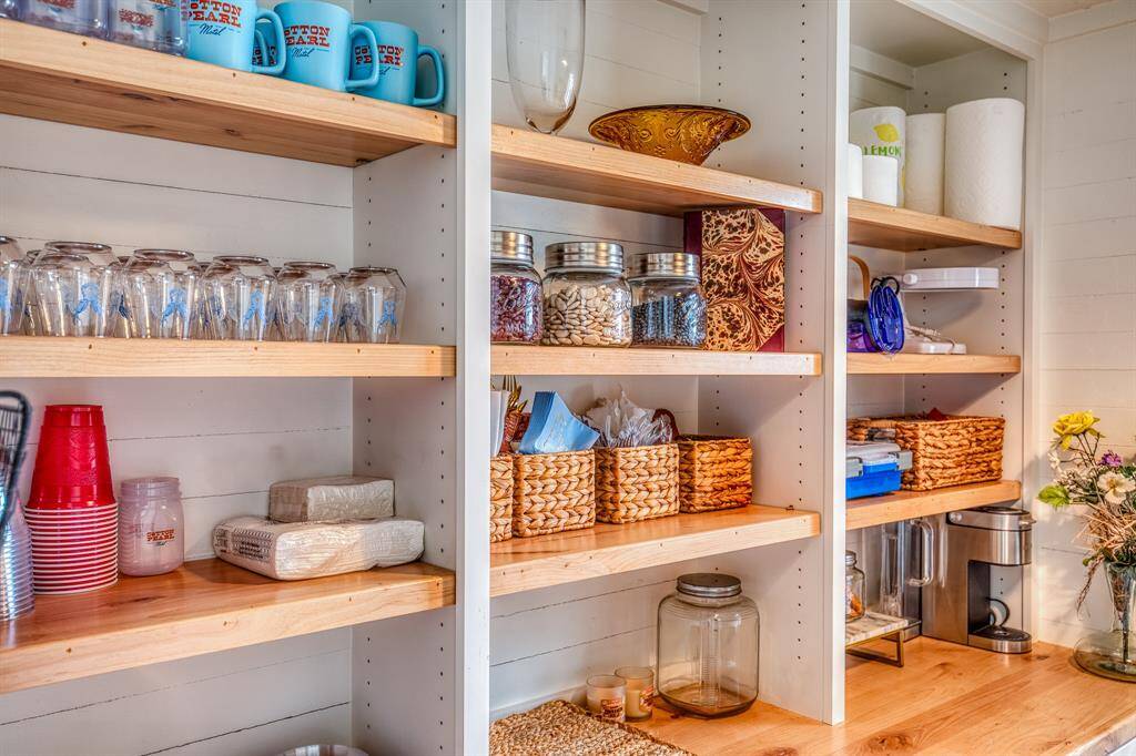 Everyday charm meets functional elegance in this perfectly styled pantry. Glassware, woven baskets, and vintage-inspired containers are thoughtfully arranged on natural wood shelves.