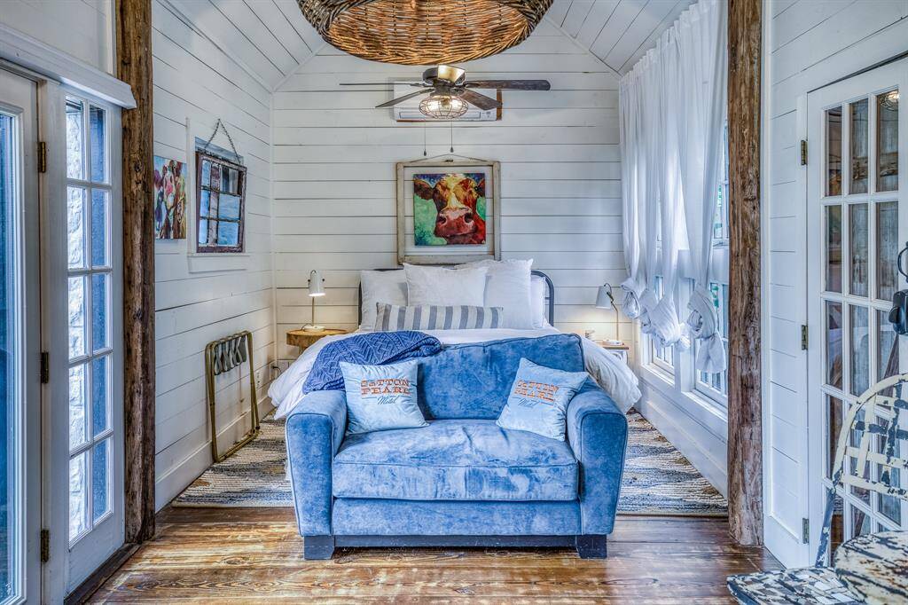 Tucked under vaulted ceilings, this whimsical suite features cozy textures, rustic wood beams, and a rattan chandelier that anchors this space.