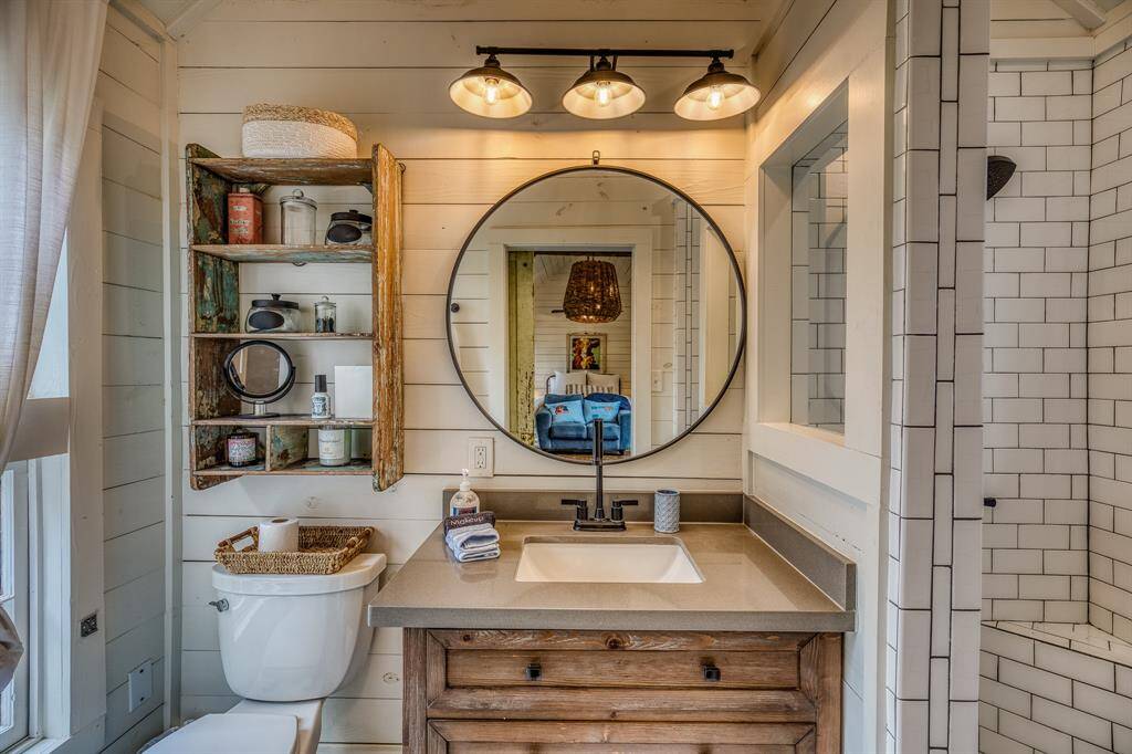 A modern farmhouse feel meets vintage charm with sleek fixtures, crisp subway tiles, and a bold round mirror that anchors the thoughtfully designed space.