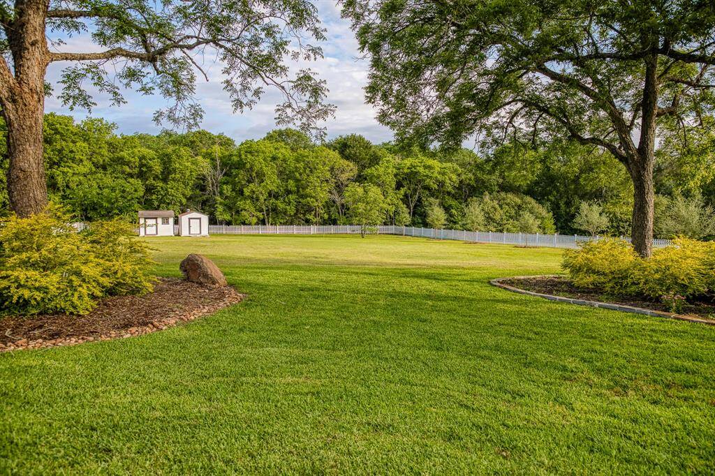 Endless opportunities await on this picturesque open field, complete with distant sheds and framed by a lush tree line—perfect for hosting outdoor events or creating your dream garden.