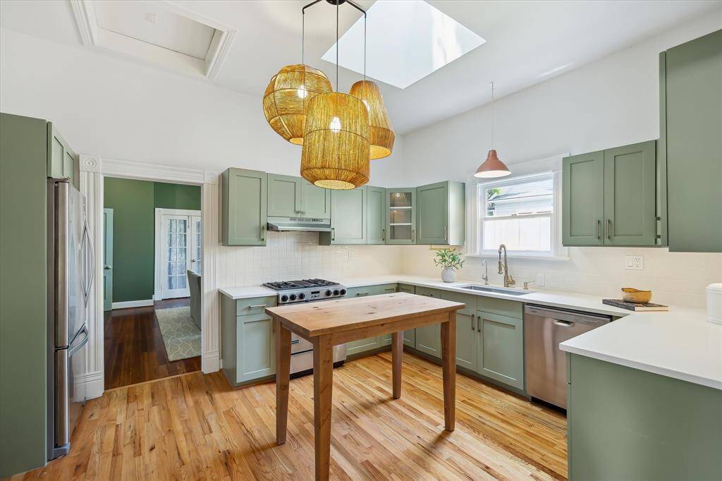 Another view of kitchen showing dining room beyond. Three pendant lights over handmade custom wood island and skylight above.