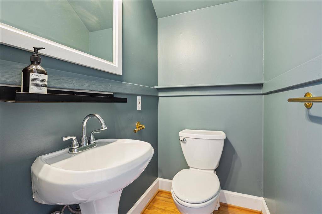 Half bath off den with brass fixtures and three-light sconce