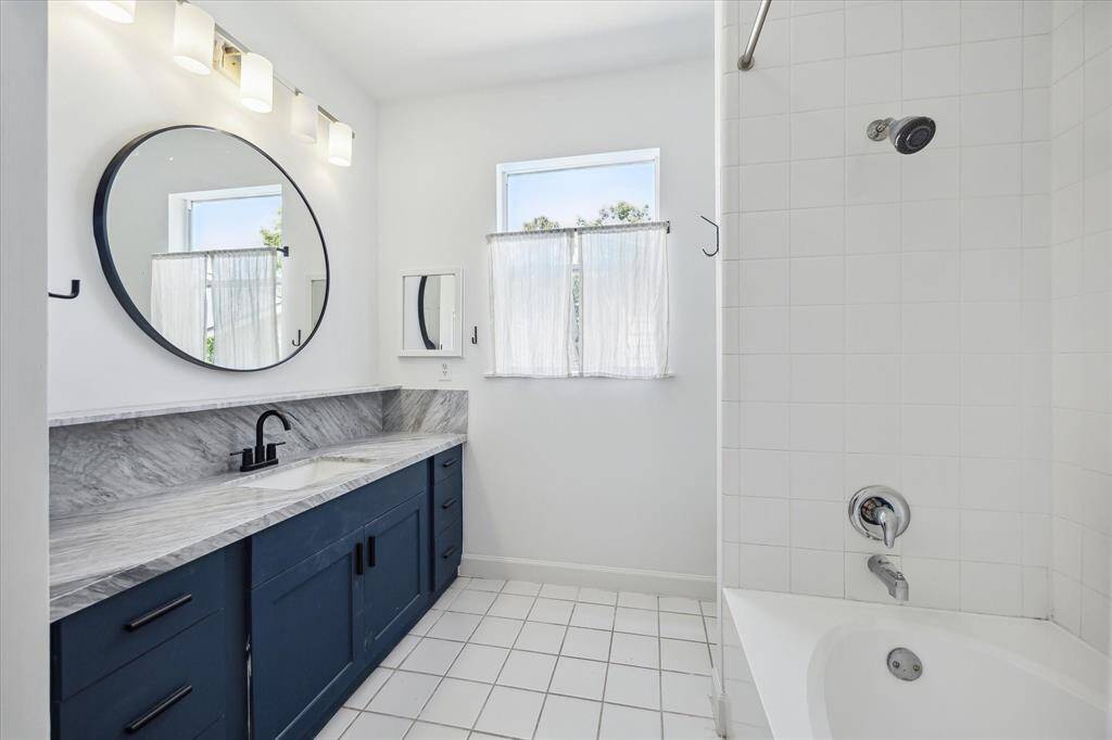 Primary bath with marble counter tops, tub/shower and built-in shelves above toilet