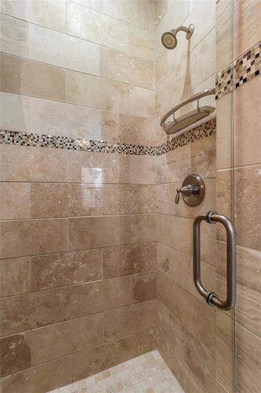 3rd Floor-Private En-Suite Bathroom Shower. Frameless glass shower door. Travertine tile walls and mosaic tiling accent the brushed nickel features.