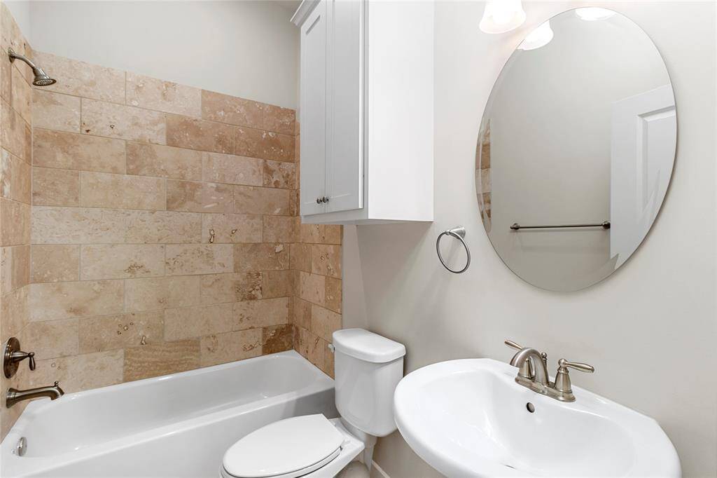 1st Floor Bedroom-Private En-Suite Bathroom features a tub and shower/tub combo with beige-tones. Classic white pedestal sink and mirror setup.