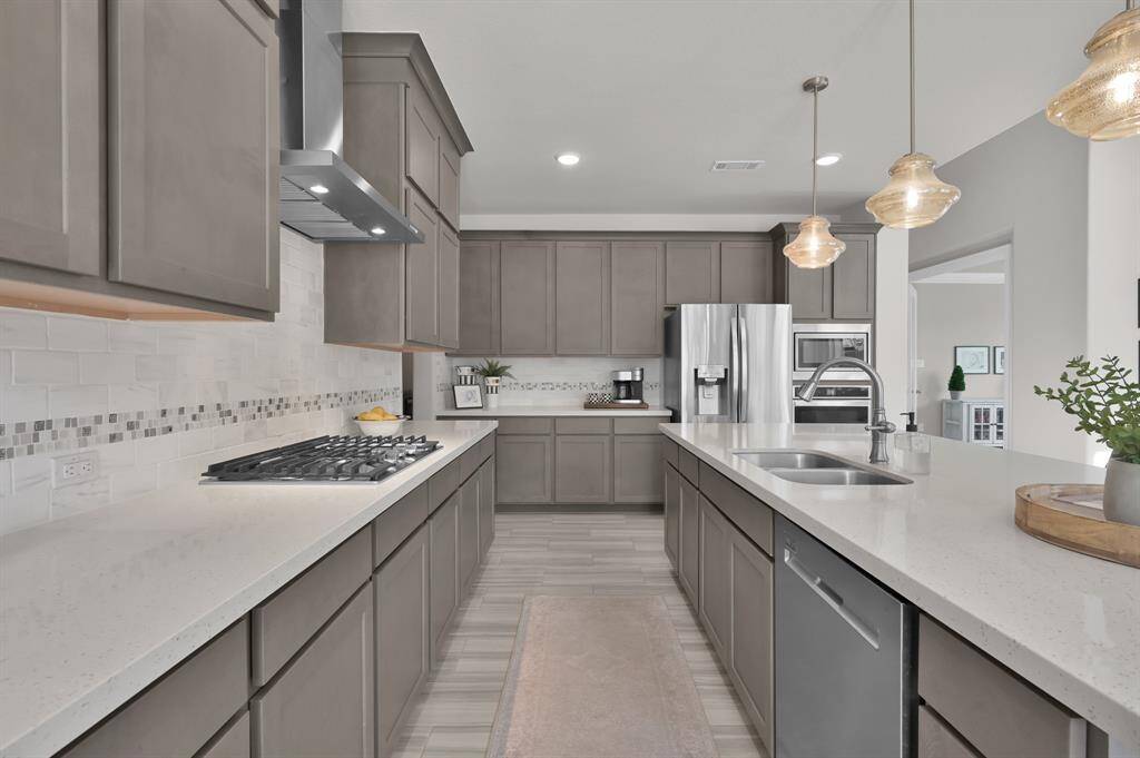 Gourmet kitchen features built-in appliances including 4-burner gas cooktop, expansive island perfect for entertaining, upgraded pendant lights, shaker-style cabinetry, and a bright breakfast/dining nook.