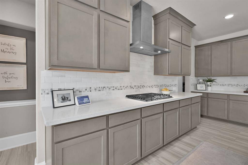Gourmet kitchen features built-in appliances including 4-burner gas cooktop, expansive island perfect for entertaining, upgraded pendant lights, shaker-style cabinetry, and a bright breakfast/dining nook.