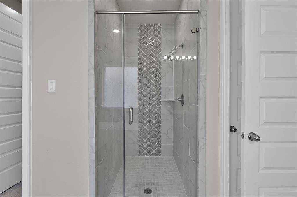Spa-like en-suite bathroom featuring dual vanities, a standalone soaking tub, oversized, Texas-sized walk-in shower with upgraded tile, and two large walk-in closets.