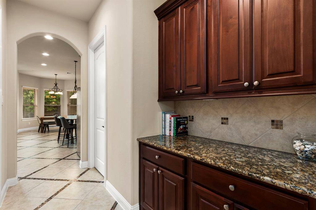 The butler's pantry offers a large granite countertop with coordinating backsplash and upper and lower cabinets for wonderful storage options.