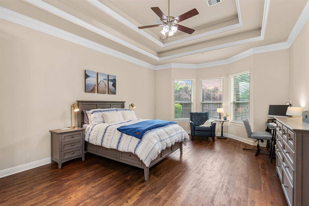 The primary retreat is large with pretty flooring, tray ceiling with crown molding and a trio of windows that fill the space with beautiful, natural light and provide views of the pretty backyard.