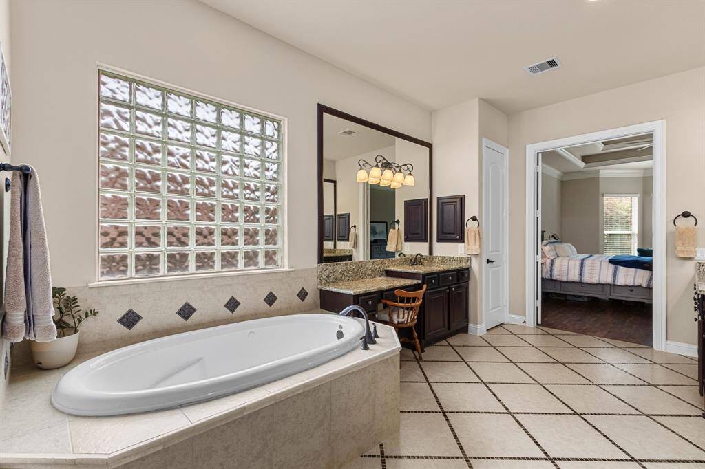 The ensuite bath is large with double vanities and a wonderful, jetted tub situated below a brick, privacy glass window.