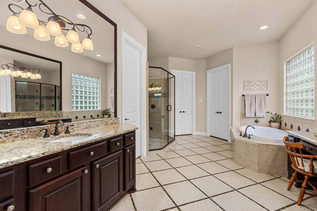 Each vanity in this spa-like bath is granite topped with expansive framed mirrors and pretty, overhead, designer lighting