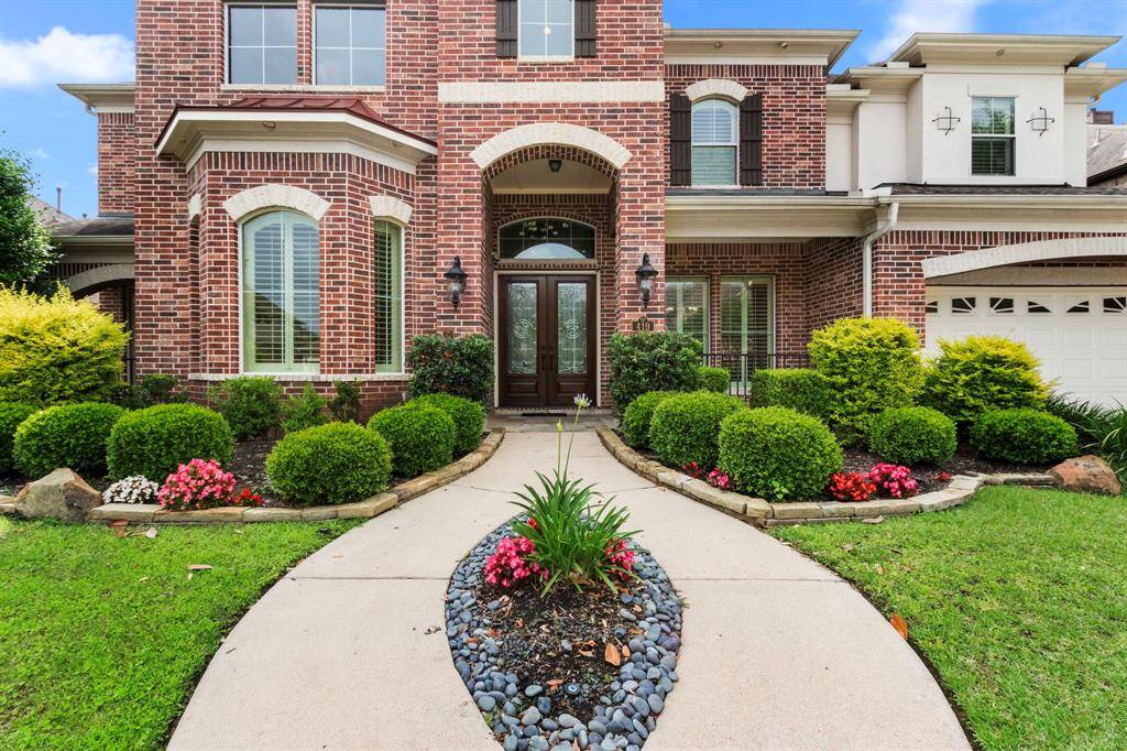 A pretty landscaped walkway leads to the spacious, arched, covered front porch.