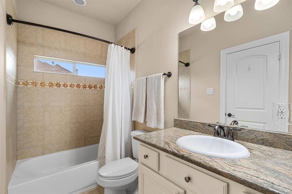 A pretty private bath with granite topped vanity, large mirror and pretty lighting.