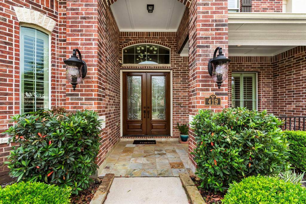 The tiled front porch with double, decorative leaded glass front doors with tandem window invites you in to this fabulous home.
