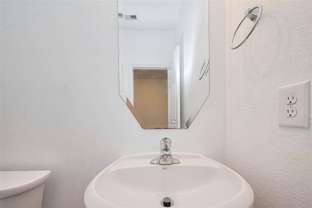Compact bathroom with a modern sink and mirror, featuring a towel ring and an accessible power outlet.