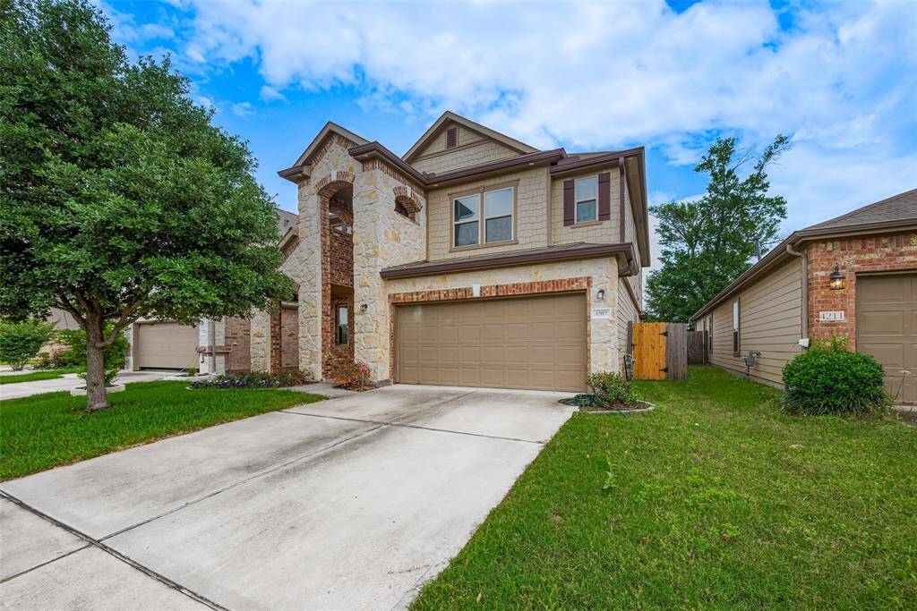This inviting two-story home features a stone and brick facade, a two-car garage, and a well-maintained lawn. It has a charming entryway, and the property is located on a quiet street with mature trees.