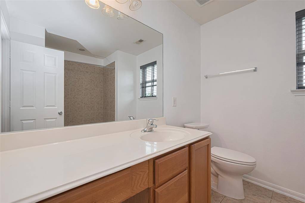 This bathroom features a clean, modern design with a large mirror, single sink vanity, and a tiled shower. Natural light comes through a window, and there's a neutral color palette for easy customization.