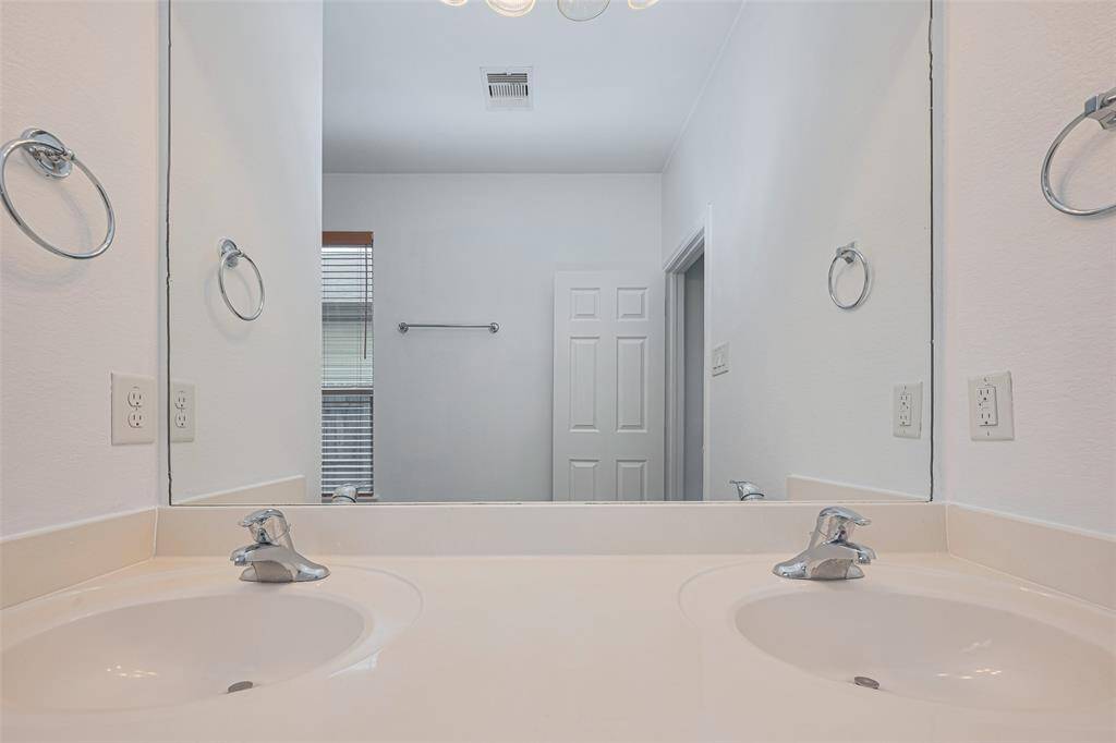 This bathroom features a double sink vanity with a large mirror, bright lighting, and a neutral color palette, offering a clean and functional space.
