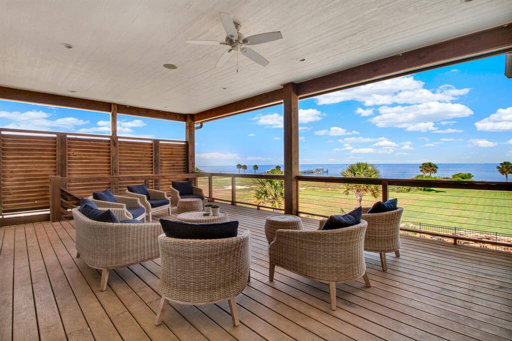 Spacious covered deck with an ocean view, a ceiling fan, and is ideal for visiting or reading a book on a lazy day.