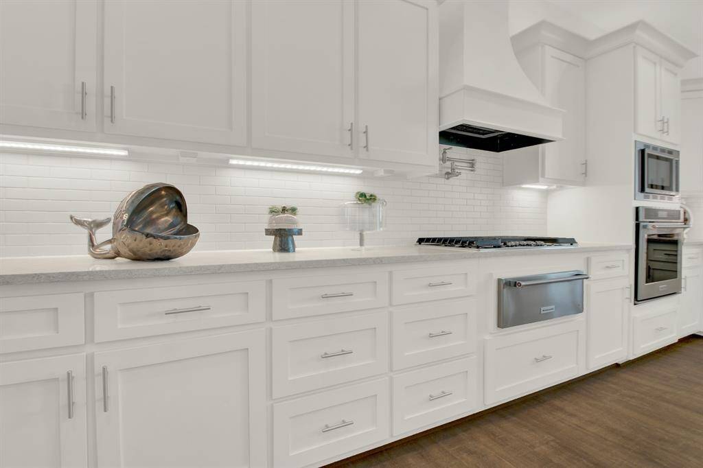 Storage will not be an issue in this kitchen! Notice the stylish subway tile backsplash, and sleek granite countertops, warming drawer, gas cook top, pot filler and large amount of storage space.
