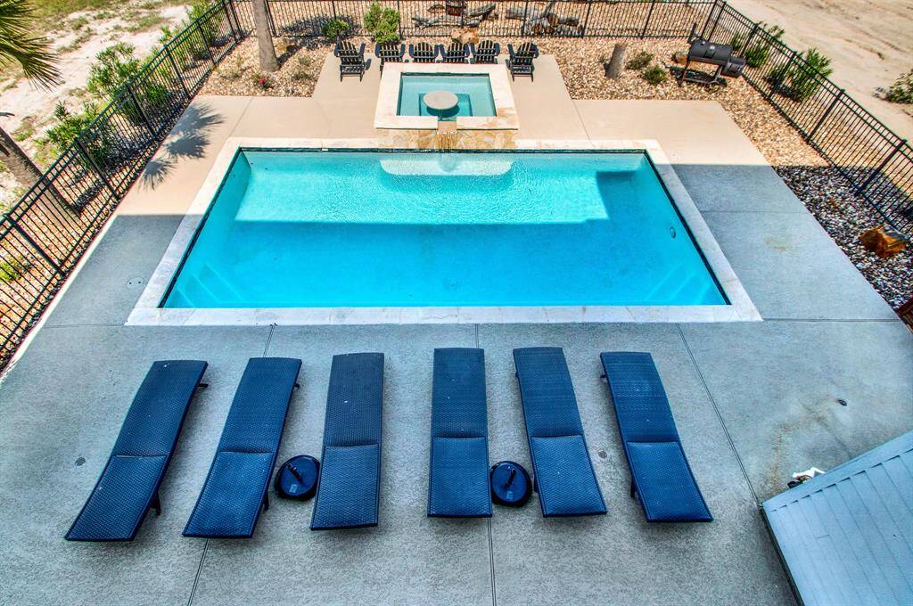 An inviting rectangular swimming pool with an attached hot tub. The area is enclosed by a wrought iron fence for privacy and safety.
