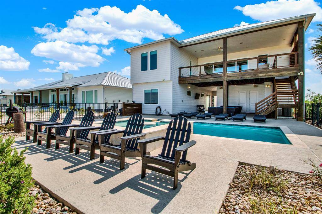 The back of the home offers a stunning water view of the bay with a spacious outdoor entertainment area, a swimming pool and enough space for lounging. The upper level boasts a covered balcony, and there's a well-maintained lawn enclosed by a fence.