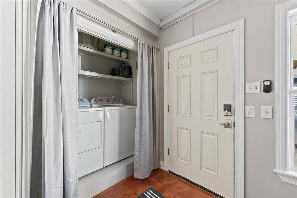 A compact laundry area with a washer and dryer tucked neatly in the storage/possible 4th bedroom. It's adjacent to an entry door, featuring shelving for storage above the appliances, offering a convenient and efficient use of space.