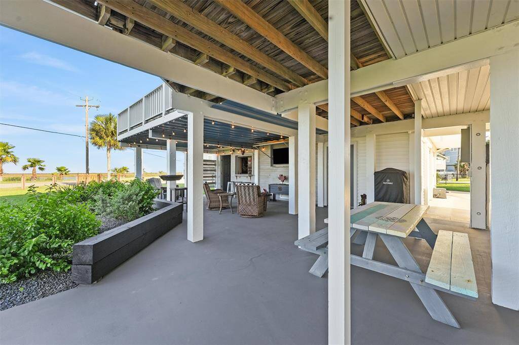 This outdoor space features a covered patio with seating and a picnic table, ideal for relaxation or entertaining. The area includes a BBQ grill and is surrounded by greenery overlooking the beautlful backdrop offering a peaceful atmosphere with views of canal, palm trees and open skies.
