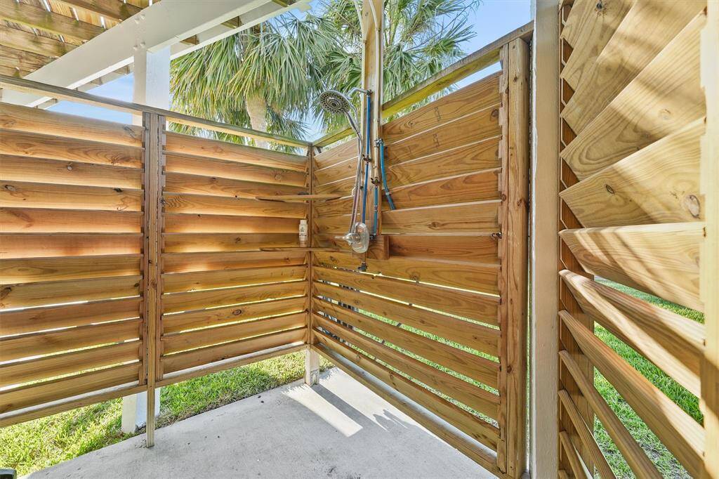 This photo features a charming outdoor shower with wooden privacy walls, perfect for a beachside or poolside home, offering a refreshing and convenient way to rinse off while enjoying nature.