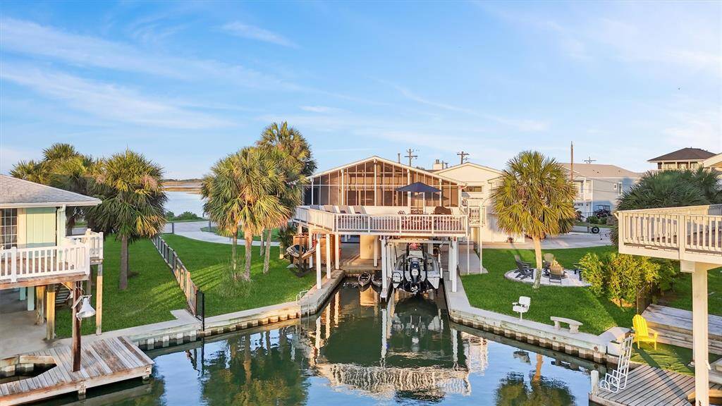 This waterfront home features a spacious deck overlooking a canal, surrounded by lush palm trees and well-maintained lawns. It includes a private boat dock and offers serene water views, ideal for boating enthusiasts and outdoor relaxation.