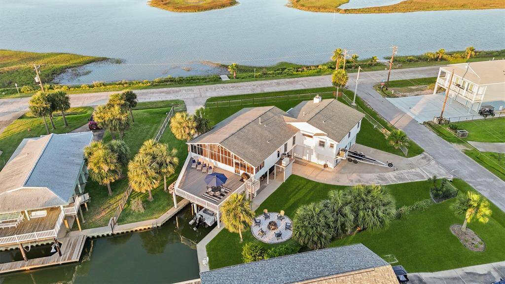 This waterfront property features a spacious house with a large deck and beautiful views of the water. It's surrounded by lush greenery and has easy access to a nearby canal, perfect for boating or fishing enthusiasts.