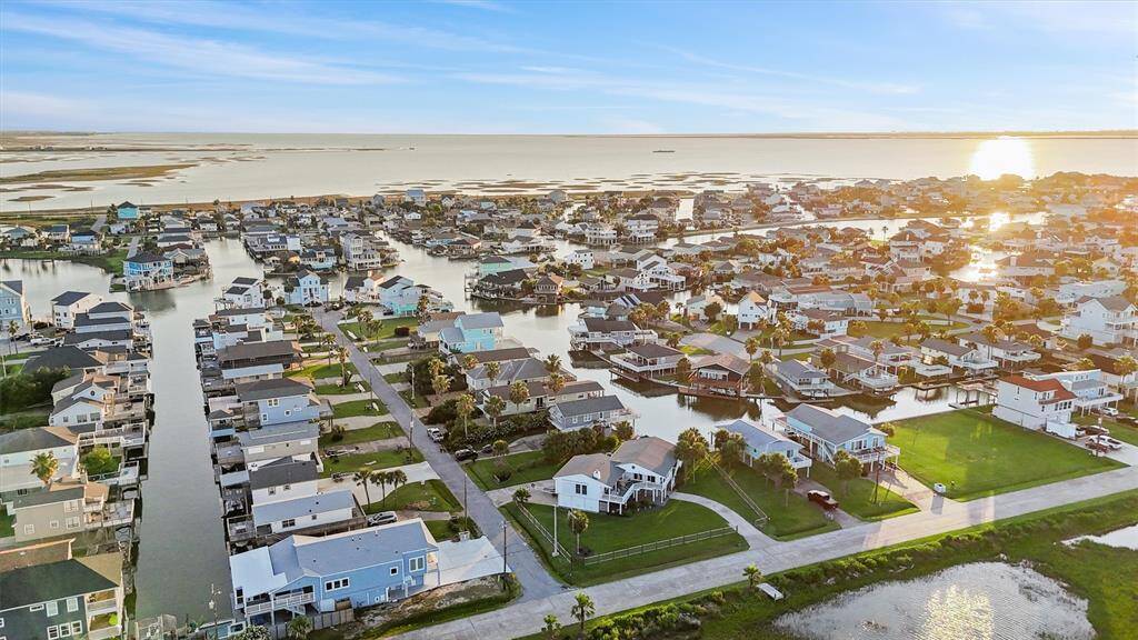 This photo showcases a picturesque waterfront community with numerous homes along a network of canals. The area is bathed in warm sunlight, offering stunning views of the water and a serene setting perfect for boating and leisure activities.
