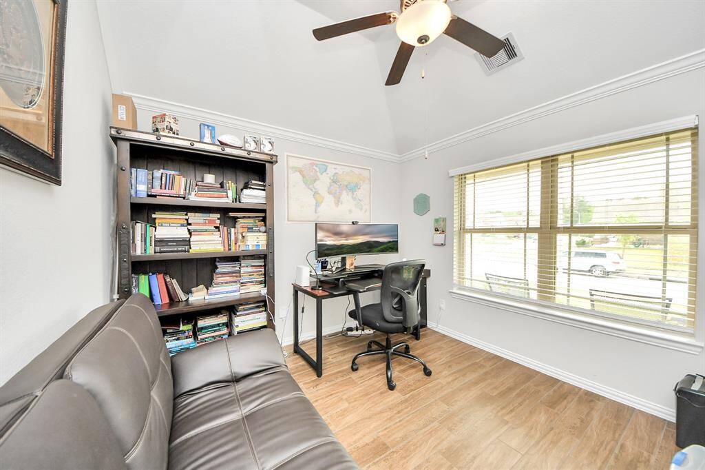 The wood-like tile continues into the office room, which has high ceilings and a ceiling fan.