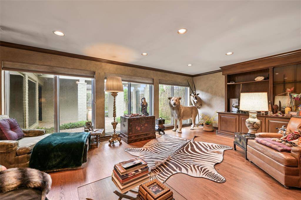 Enjoy the warm and inviting den with rich wood tones, custom built-ins, and floor-to-ceiling windows that overlook the private courtyard.