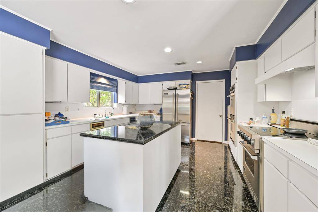 A classic white kitchen with bold blue accents, granite countertops, double ovens, and stainless steel appliances—ready for your culinary creations.