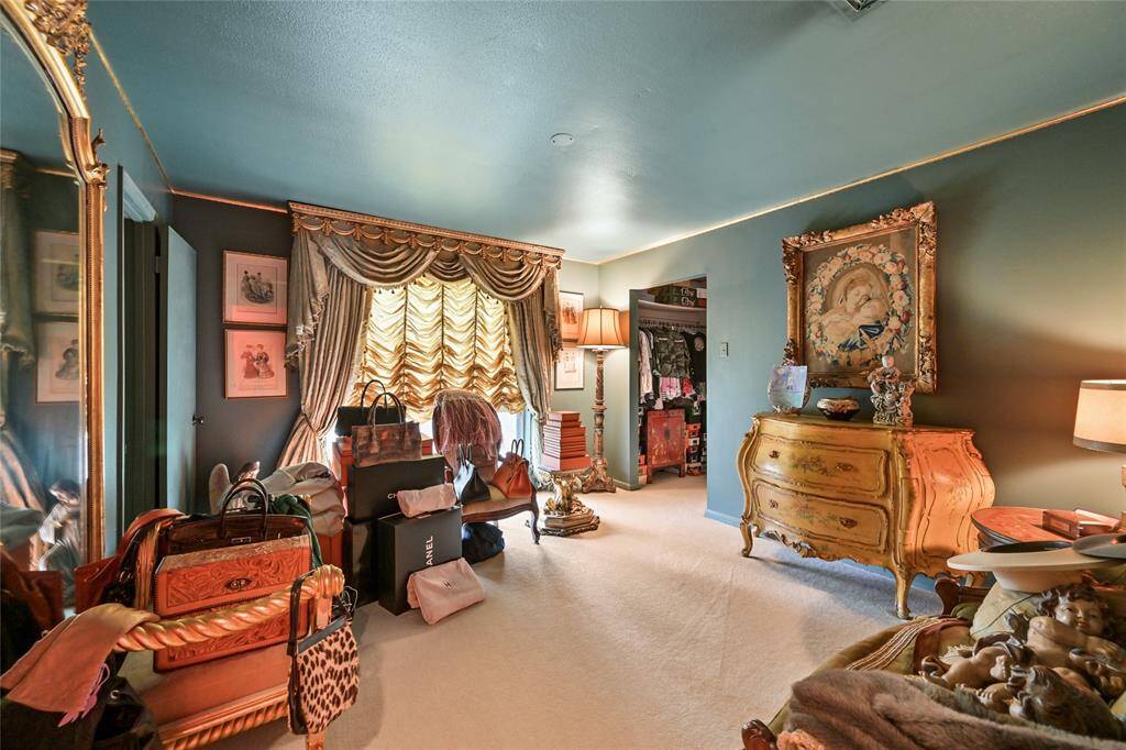 Step into the lavish secondary bedroom that feels like a luxury boutique, complete with custom drapery, ornate furnishings, and a walk-in closet.