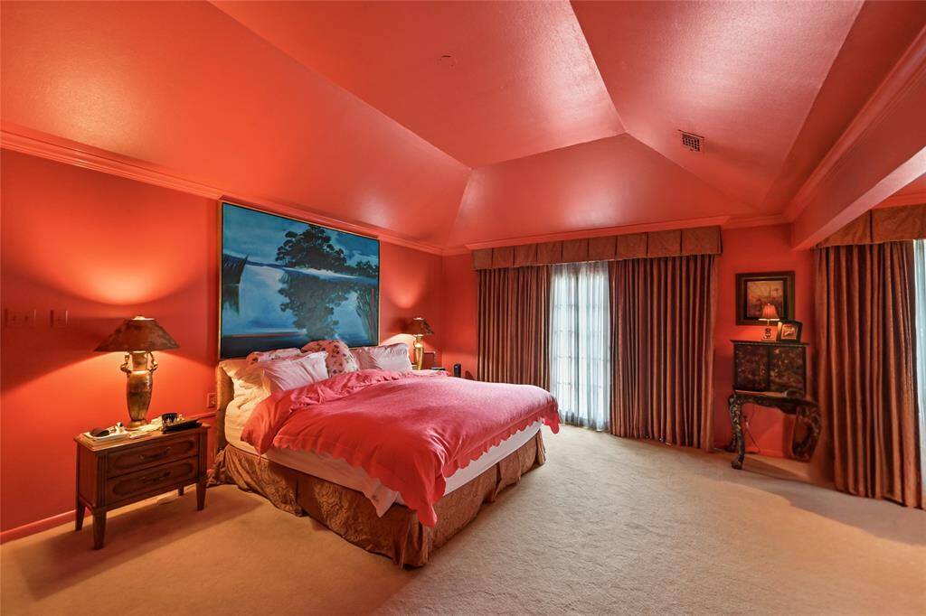 The spacious primary bedroom is a true retreat with statement-making walls, plush carpet, and abundant natural light streaming through elegant drapery.