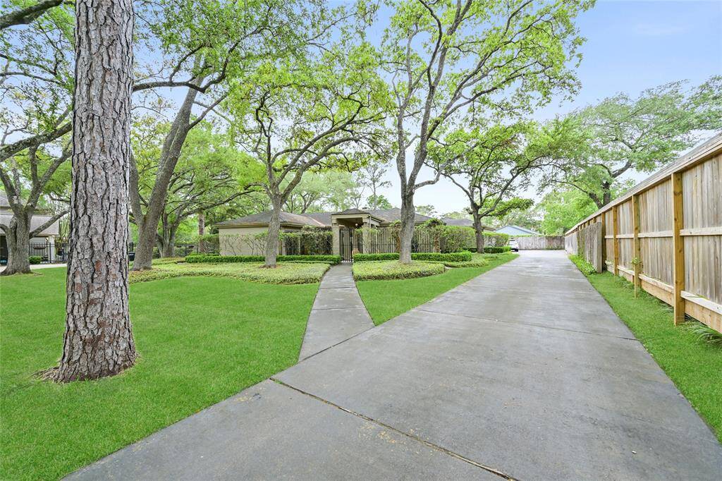 An extra-long driveway welcomes you through a lush, tree-shaded front yard, offering ample parking and a private approach to this charming Piney Point residence.