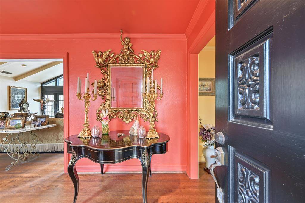 Step inside through the double door entry to a dramatic foyer adorned with intricate molding, antique-style candelabras, and a striking mirror that adds instant glamour to your grand entrance. Wood flooring flows through the home's main spaces.