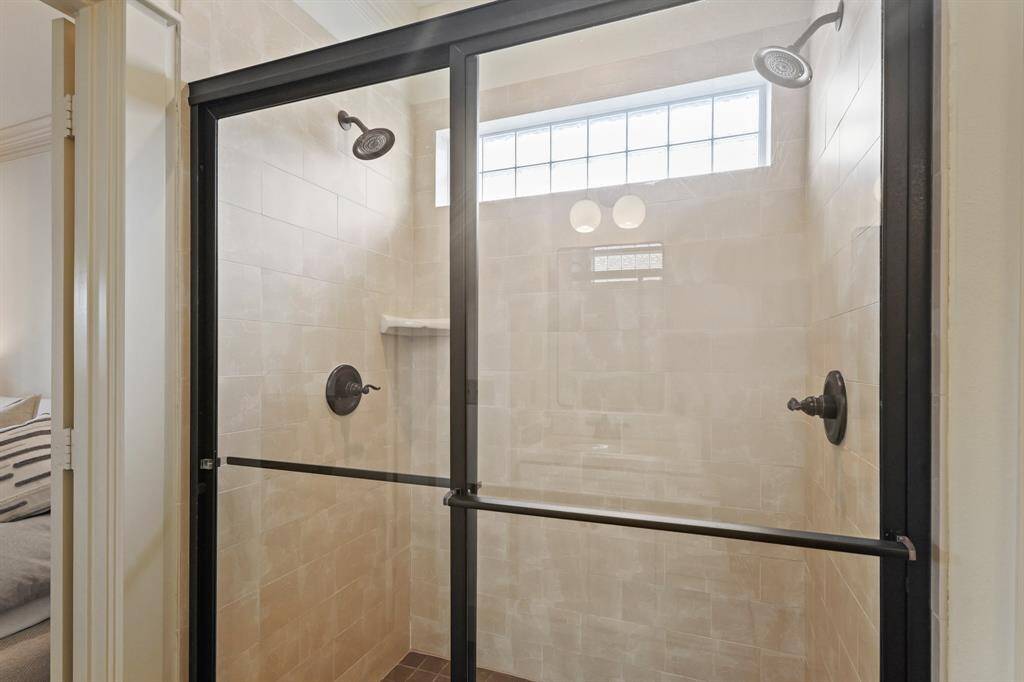 Large shower with sleek, modern tiles, a glass door, and ample space for comfort and relaxation