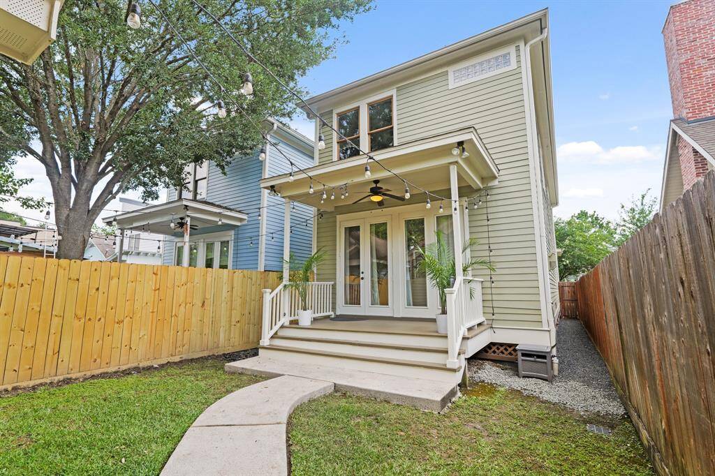 View from the yard showcasing French doors flanked by French-style windows, adding charm and symmetry to the back of the home while inviting natural light inside