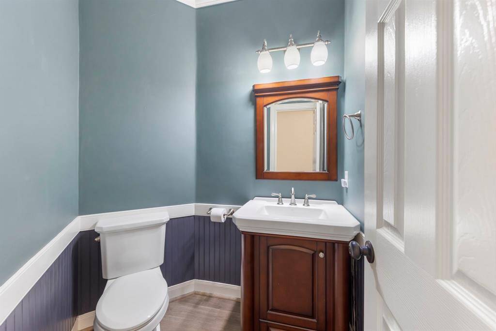 This elegant powder room, where modern charm meets classic wood accents. The rich vanity and calming color palette create a serene escape, perfect for guests.