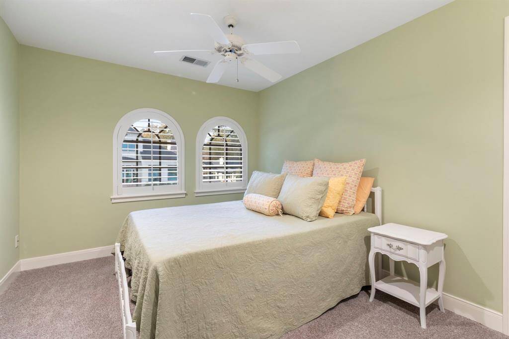 This secondary bedroom, promise restful nights. The charming arched windows with plantation shutters not only enhance privacy but also invite in natural light, creating a tranquil atmosphere.